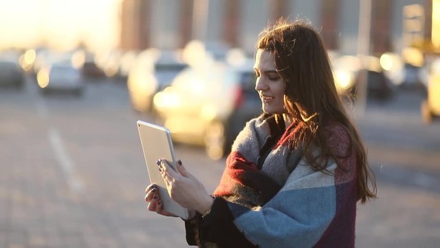 Pretty toung girl model communicating with someone through the pad in the urban sunny street