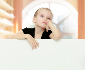 The girl peeks out from behind white banner.