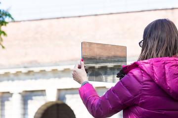 woman in a city taking photographs with transparent tablet