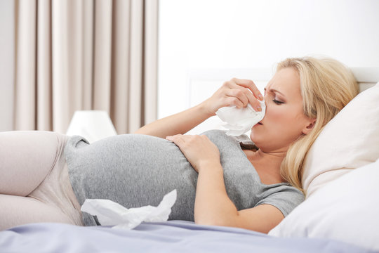 Pregnant woman with allergy lying on bed at home