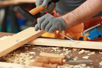 Carpenter with chisel and hammer in workshop, closeup