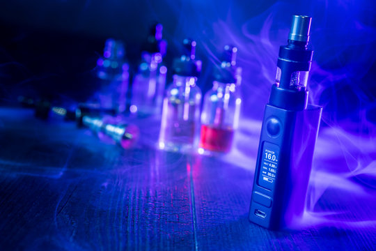 Vape devices, E-cigarette for vaping, liquid in the bottle on wooden table.