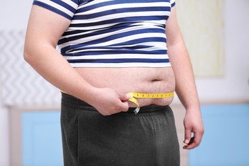 Fat man with measuring tape at home. Weight loss concept