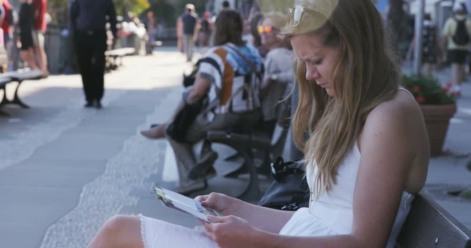 girl sitting on bench on pier reading