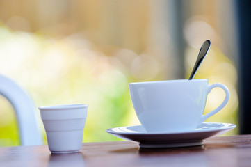 A spoon in cup of coffee on the table, blurry beautiful background