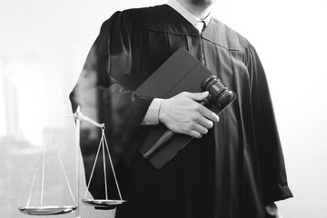 justice and law concept.Male judge in a courtroom with the gavel and balance scale and holy book and digital tablet computer