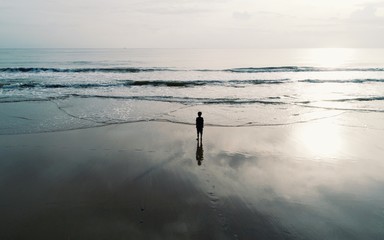 silhouette man standing alone on beach