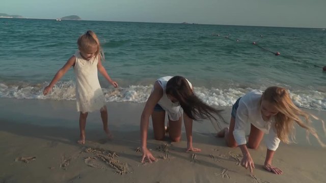 Happy mother and her daughters are painting on the sand of beach of South China Sea stock footage video