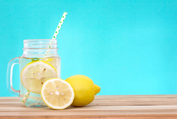  Citrus lemonade water with lemon sliced , healthy and detox water drink in summer on wooden table...