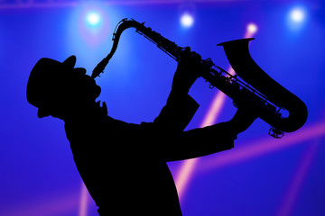 Naklejka premium Man playing on saxophone against the background of beautiful light