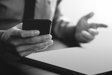 close up of businessman working with mobile phone and laptop computer on wooden desk in modern office with virtual reality icon diagram