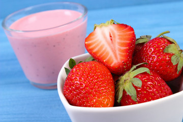 Fresh strawberries and delicious milkshake on blue boards, healthy dessert