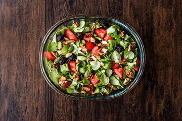 Purslane salad with walnut, tomatoes and olive on wooden surface.