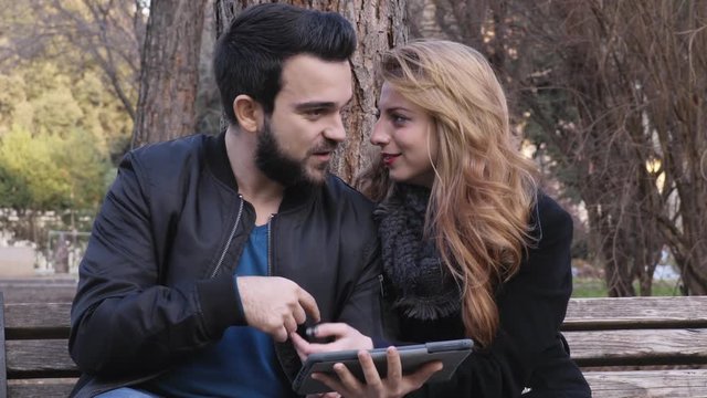 young attractive couple using tablet computer at a park
