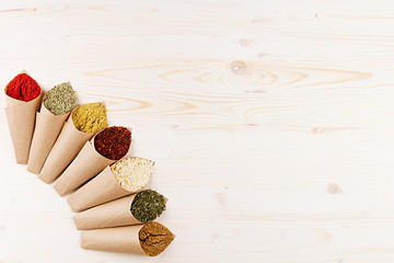Asian colorful powder spices in rustic paper corner on white wooden board with copy space.