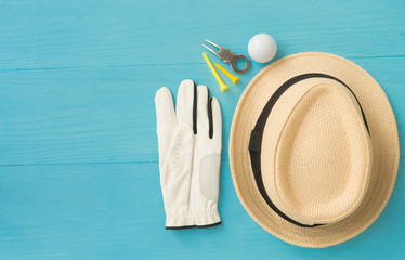Golf concept : panama hat, glove, golf balls, golf tees, divot repair tool on wooden table. Flat lay with copy space.