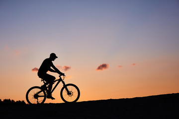 Obraz premium cyclist on the sunset sky background. silhouette of a man on a bicycle