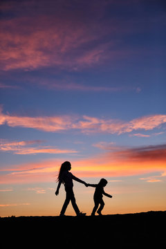 Children hold hands. children's silhouettes on sunset background