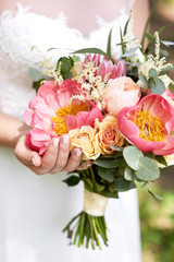 Fototapeta na wymiar pink peony bouquet in hands of the bride