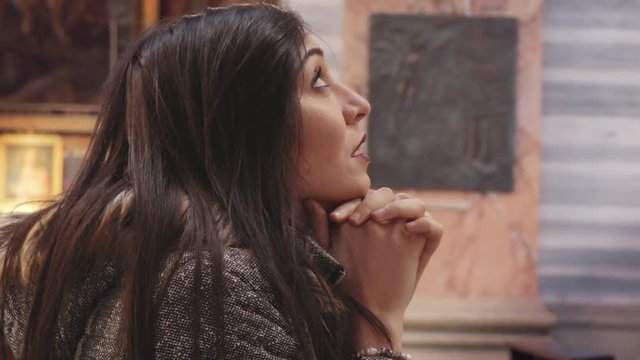 Sad and believing young woman in church pray god