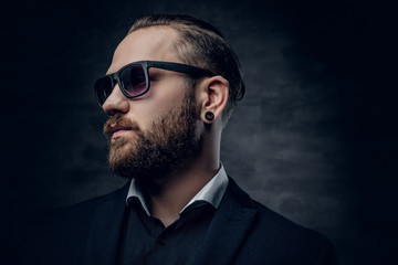Fototapeta premium Stylish bearded male in sunglasses over dark grey background.
