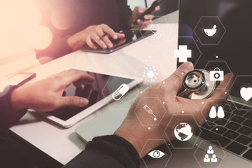Medical co working concept,Doctor working with smart phone and digital tablet and laptop computer to meeting his team in modern office at hospital with virtual diagram