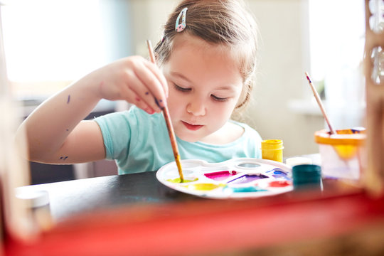 little girl mixes paint. child draws paints