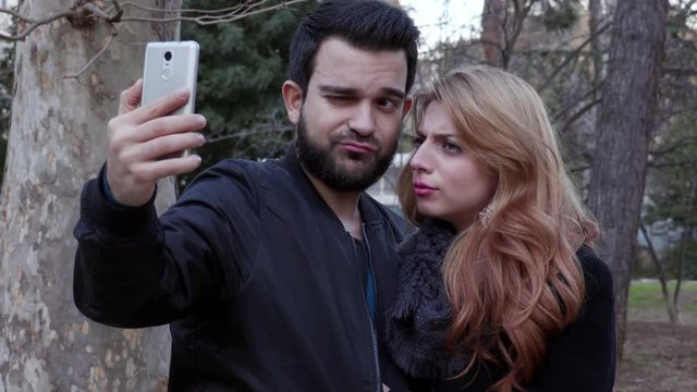 happy beautiful couple taking funny selfie at the park,winter time