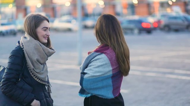 Two young beatiful pretty student stylish girls talking and laughing on the urban street near the cars, Steady cam, slow mo shot
