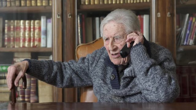 Old man talks on mobile phone at home
