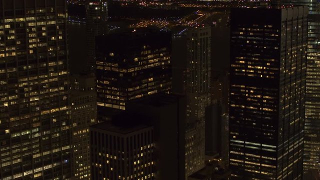 AERIAL HELI SHOT CLOSE UP Flying close to the windows of modern glassy office buildings, tall skyscrapers and luxury residential condominiums with lights turned on in New York City Downtown Manhattan