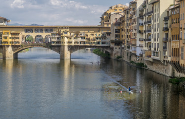 Fototapeta na wymiar Rowing boats navigate the Arno river near the famous Ponte Vecchio bridge, historic center of Florence, Italy