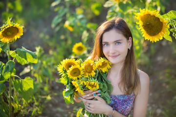 Cute beautiful young girl lady woman sitting on a field with big sunflowers.Brunette with blue eyes...