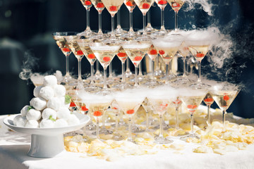 Champagne pyramid on event, party or banquet. cherry in the glass. Dry ice floats