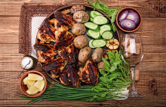 Chicken wings with baked potatoes  and wine glass on wooden background.  