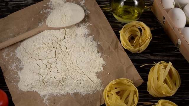 pasta, eggs, oil, tomatos, garlic and flour on wooden background