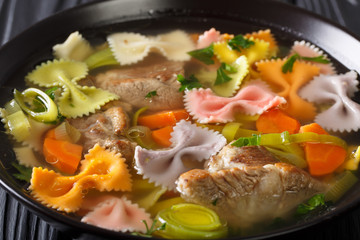 Broth with pasta farfalle and vegetables close-up. horizontal