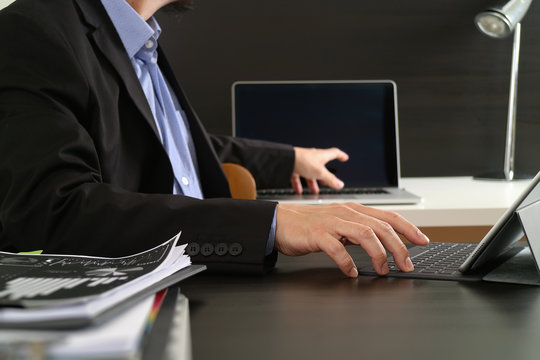 businessman using digital tablet and laptop computer and document in modern office