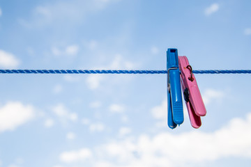 Blue and red clothespins on a clothes line in front of a blue sky