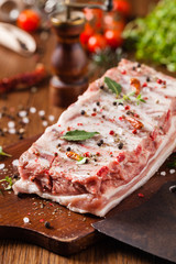 Raw pork ribs, on a plate sprinkled with spices.