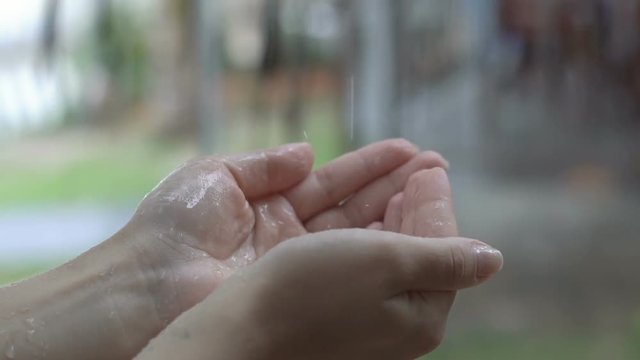 Water drops in hand. Rain water drops falls in a female hand in slow motion.