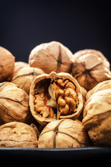 Walnuts. Nuts of walnuts. Nuts in black plates against the background of a black wooden background. Rustic. Fresh autumn walnut harvest in the village. Place for text