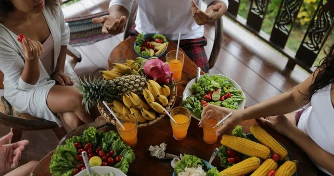 People Clink Juice Glasses, Table With Dishes Of Tropical Fruits And Salad Top Angle View Friends Eating Healthy Vegetarian Food Slow Motion 60