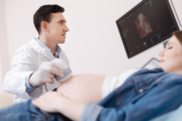 Involved young gynecologist using equipment for sonogram at work