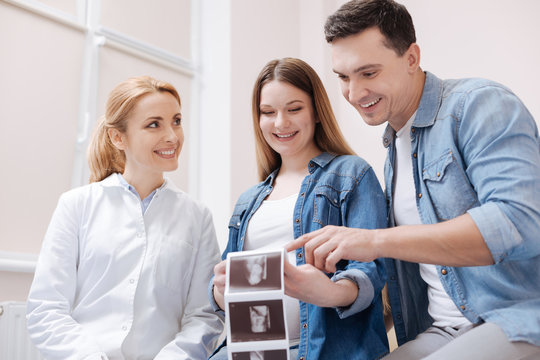 Delighted couple enjoying ultrasonic scan of future baby in the clinic