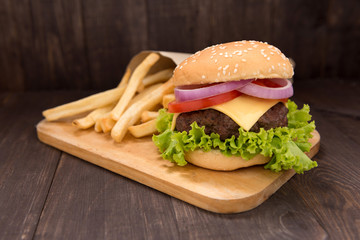 Cheeseburger with french fries on wooden background