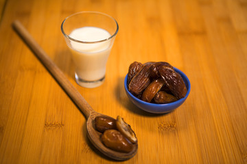 cuillère de bois avec dattes et verre de lait