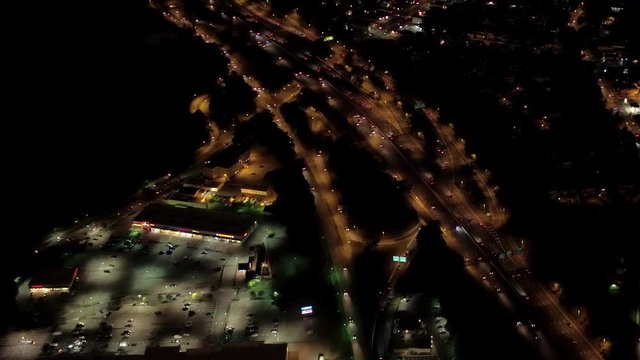 AERIAL HELI SHOT: Big interchange with overpass underpass system at high volume urban and suburban traffic intersection in United States of America. Cars and semi trucks traveling along busy highway