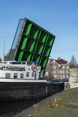 Green modern drawbridge with big boat under it in the day in Amsterdam