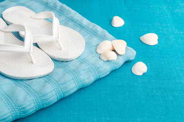 White flip flop near seashell on blue background. Summer. Vacation.